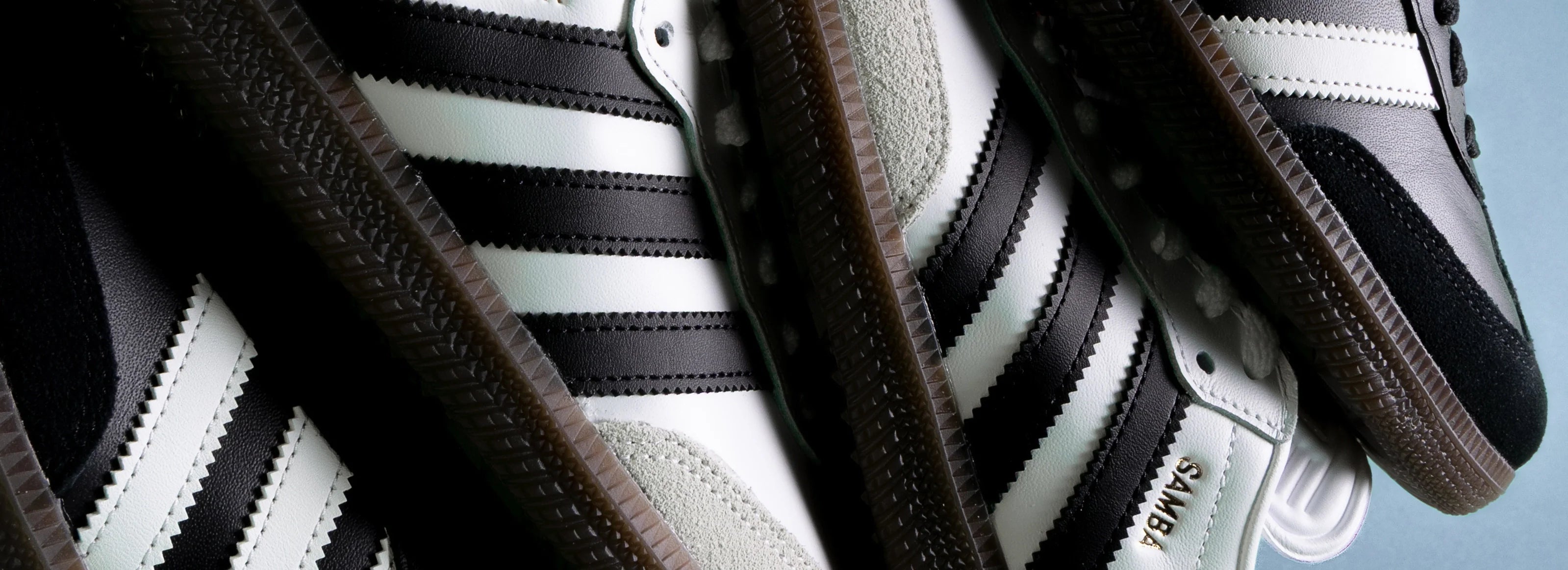 A stack of black and white Adidas Samba shoes.